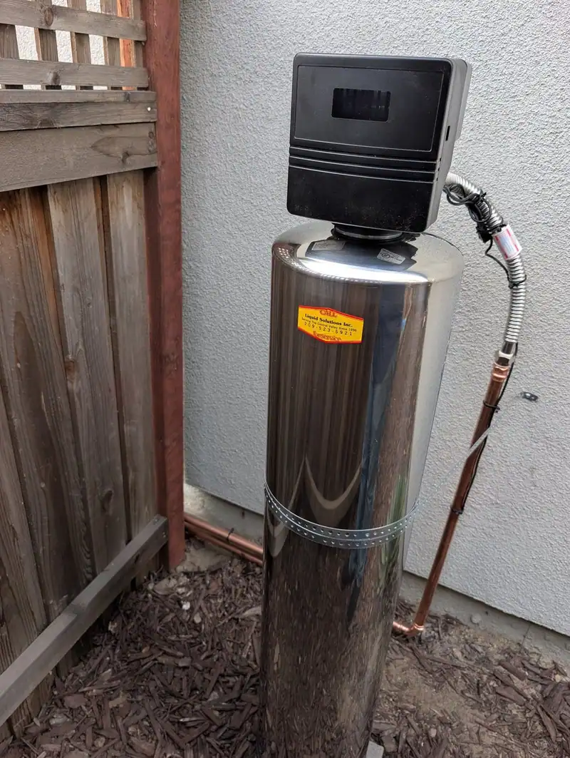 Stainless steel whole-house water treatment tank with control valve, installed by Liquid Solutions Inc