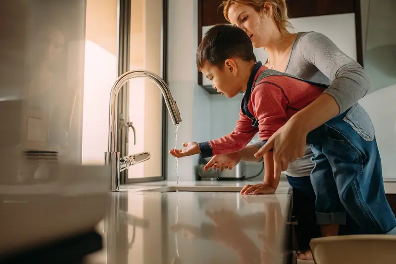 Mother and son washing hands at a kitchen sink